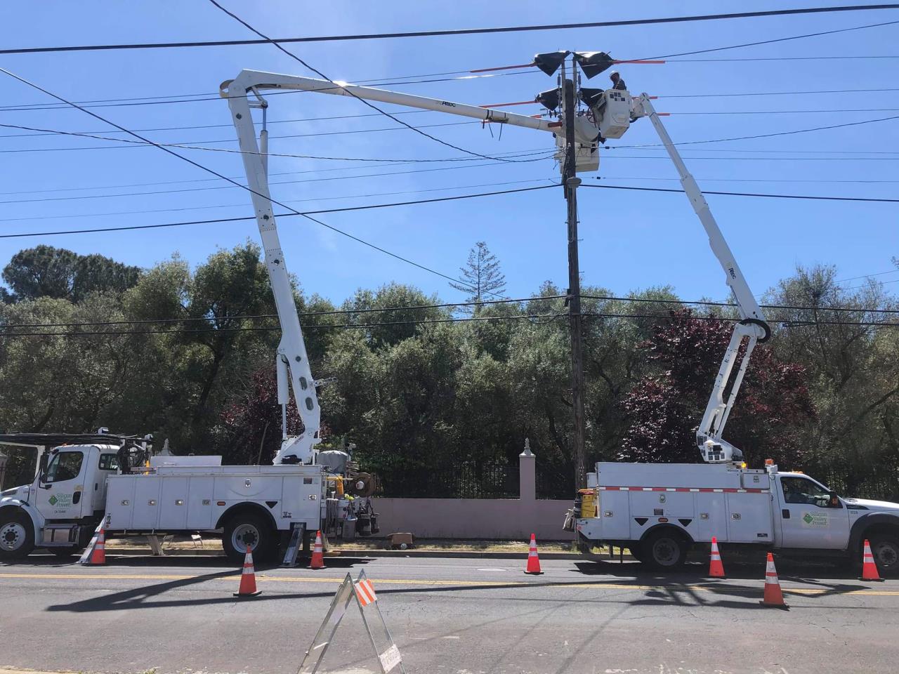 2 bucket trucks working on a power line